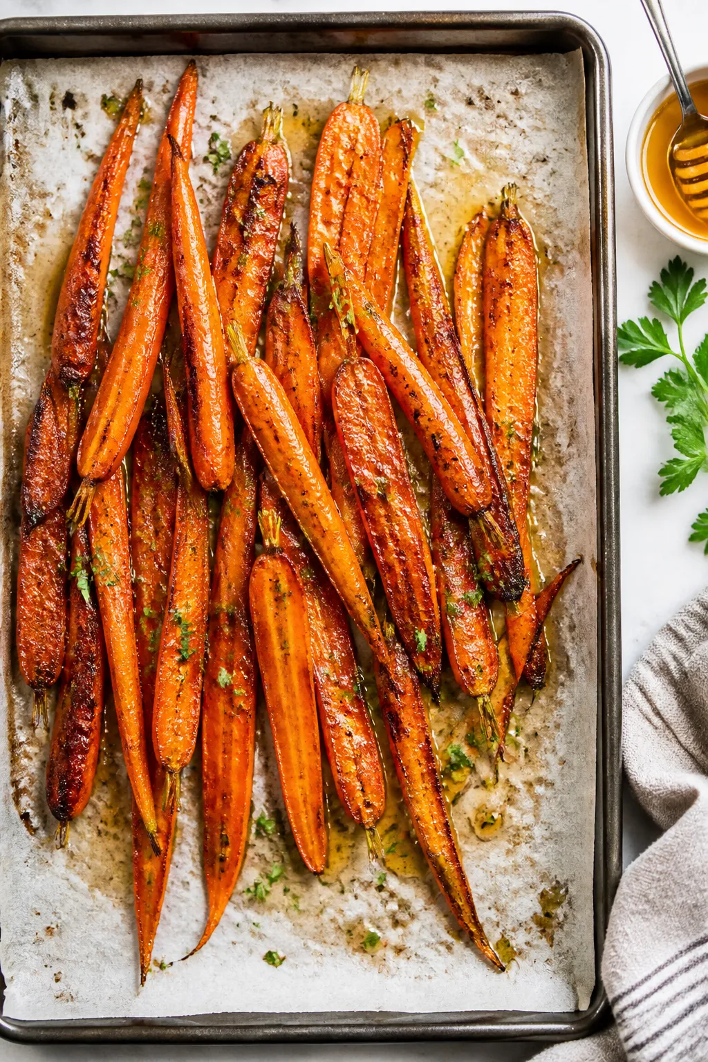 Overhead shot of honey-roasted carrots just out of the oven on a parchment-lined sheet pan, carameli