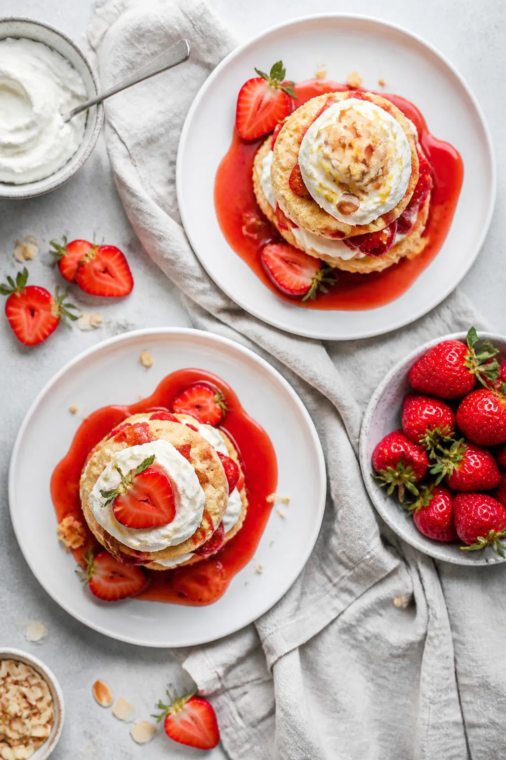 Overhead final presentation of assembled strawberry shortcakes on matte white plates: neatly stacked
