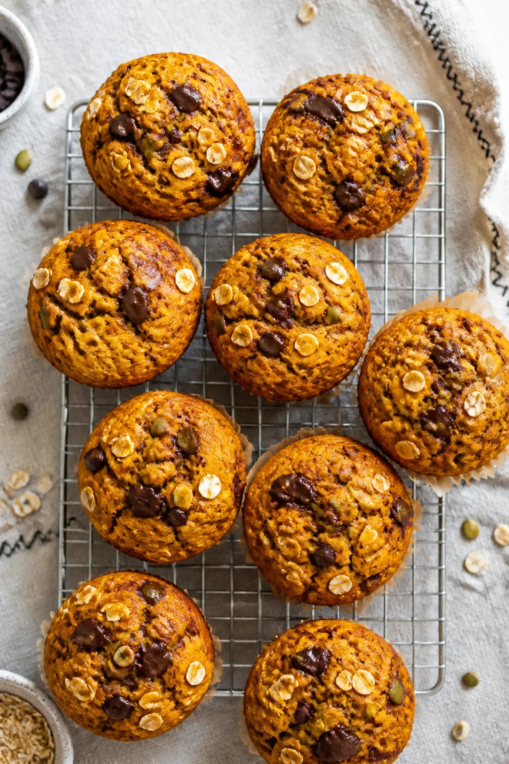 Overhead shot of freshly baked flourless pumpkin muffins cooling on a wire rack, each muffin domed a